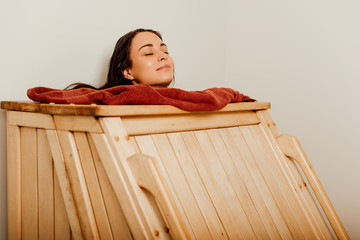 smiling woman taking steam bath with closed eyes in spa center