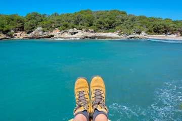 Selfie of hiking shoes, mediterranean blue water background in Menorca, Balearic islands, Spain