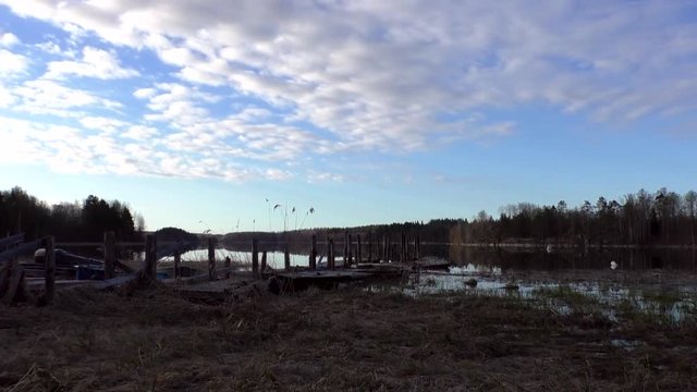 Low Clouds fly over the lake and old wooden pier. Landscape coastline with wharf in the Northern wildlife. 