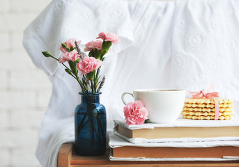 Home interior: flowers in vintage bottles, books and coffee mug close-up