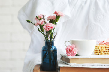 Home interior: flowers in vintage bottles, books and coffee mug close-up