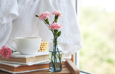 beautiful pink carnations in vintage bottles, coffee and cookies, closeup