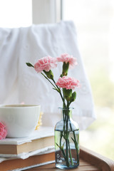 beautiful pink carnations in vintage bottles, coffee and cookies, closeup