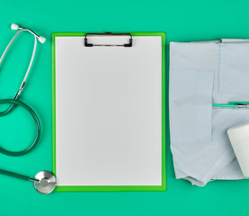 empty white sheets and a medical stethoscope on a green background