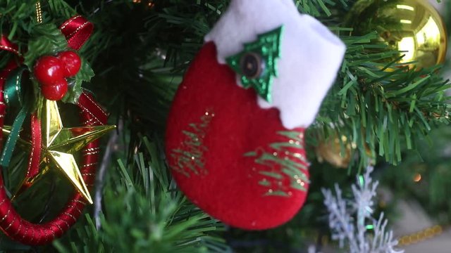 Some people put red socks on a green Christmas tree with flashing lights around the tree.