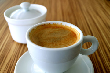 Cup of Hot Black Coffee with a Sugar Pot Served on a Table