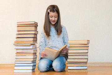 Girl reading a book sitting on the floor in an apartment. Cute girl reading book at home. education and school concept - little student girl sitting on floor and reading book