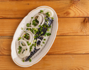 Salted mackerel slices and onions on a plate on the table.