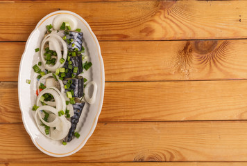 Salted mackerel slices and onions on a plate on the table.