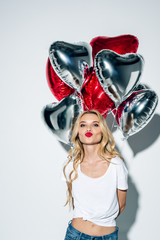 attractive blonde girl with duck face holding balloons on white