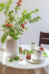Morning table with coffee, caneles and flowers. Bright mood still life with food.
