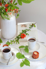 Morning table with coffee, caneles and flowers. Bright mood still life with food.