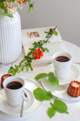 Morning table with coffee, caneles and flowers. Bright mood still life with food.