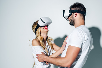 happy man touching blonde woman while wearing virtual reality headset on white