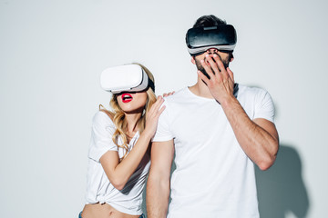 surprised man and woman wearing virtual reality headsets on white