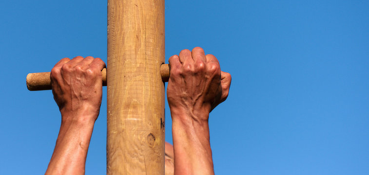 A man climbs onto a pillar, hands detail - Powered by Adobe
