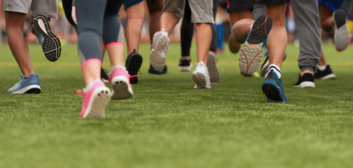 Fototapeta premium Running children, young athletes run in a kids run race, running on grass detail on legs, running in the light of morning