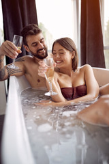 Romantic moments in the bathroom - Couple Relaxing In Bubble bath and drinking champagne.