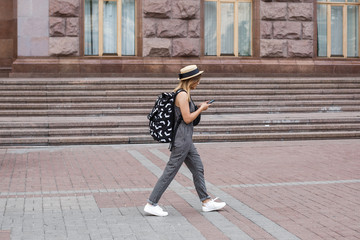 Happy traveling fashion girl in sunny downtown. Straw hat and backpack.