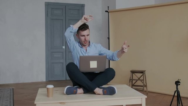 Businessman sitting in the lotus pose on the table. He visualizes new solutions for the development of his start-up. Suddenly he gets vision and insight. A joyful person begins to work.