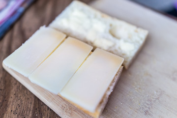 Hard parmesan cheese slices on cut fresh baguette or white bread dairy food