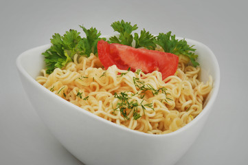 Instant vermicelli with tomato and parsley on a gray isolated background
