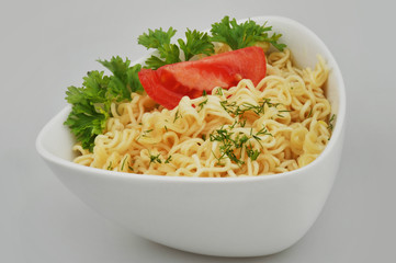 Instant vermicelli with tomato and parsley on a gray isolated background