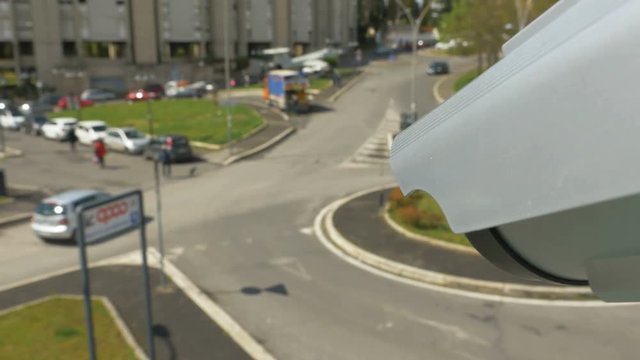 Modern roadside surveillance camera tracking every move in the city. CCTV surveillance monitoring of road with left-hand traffic. First Person View footage in 4K