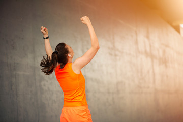  Successful female athlete raising arms