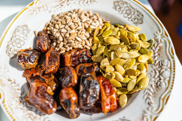 Flat top closeup of raw vegan healthy snack or ingredients with sunflower and pumpkin seeds, and dried dates for making truffles dessert on plate