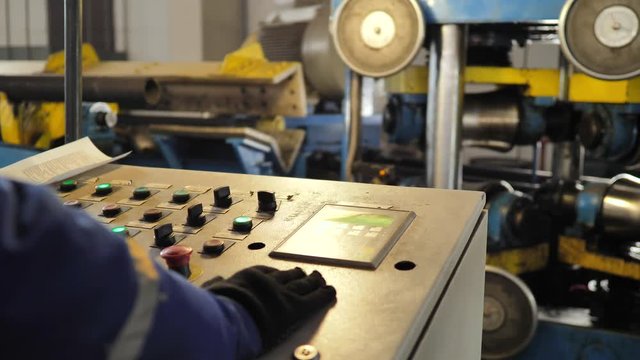 Industrial plant mechanic and factory worker customize industrial equipment control panel. Worker controls machine.