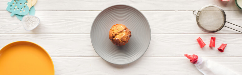 panoramic shot of delicious muffin and baking tools on wooden table
