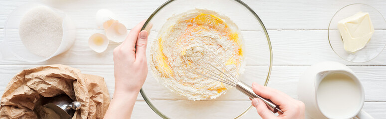 panoramic shot of woman mixing dough in bowl on table