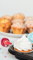 selective focus of delicious cupcakes decorated with sprinkles in cupcake tray isolated on grey