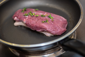 Chef fries duck breast on pan in restaurant kitchen