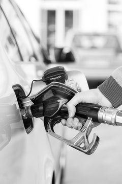 Pumping Gas At Gas Pump. Closeup Of Man Pumping Gasoline Fuel In Car At Gas Station. Black And White Image.