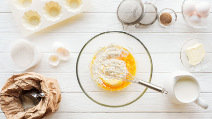 top view of bowl with dough, kitchen utensils and ingredients on table