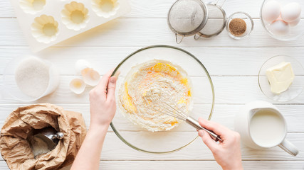 cropped view of woman mixing cupcake dough in bowl on table