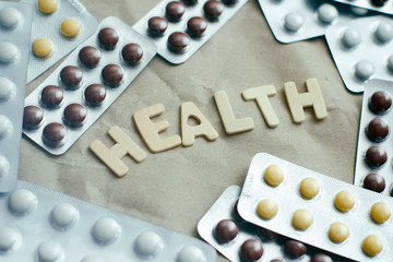Set of different colours plastic pill blisters. Health text inscription by wood letters. Pharmaceutical medicine.