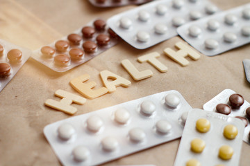 Set of different colours plastic pill blisters. Health text inscription by wood letters. Pharmaceutical medicine.