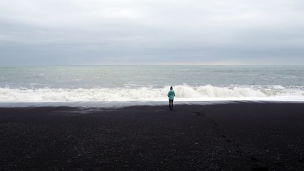 czarna plaża islandia black beach czarny piasek ocean osoba patrzy pochmurne niebo © Magdalena Grzeszyk