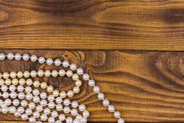 Pearl necklace on wooden background. Top view, copy space