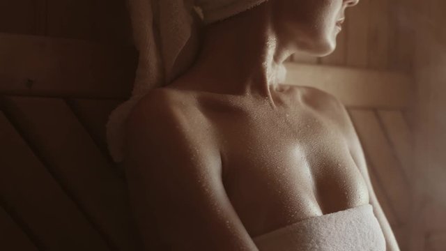skin treatments in the sauna. a girl in a white towel on her head takes skin care procedures in a Finnish sauna.