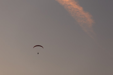 View of the paraglider in profile, side. A lone parachute in the clear sky at sunset. paraplane. The concept of freedom, sport, healthy lifestyle and travel.