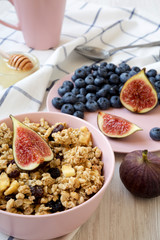 Pink bowl of fruit granola with fruits and honey, low angle view. Closeup.