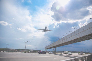 Close-up of a passenger plane flying over a highway against a blue sky