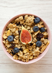 Granola with fruits in a pink bowl, top view. Flat lay, from above, overhead. Close-up.