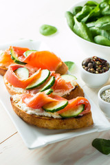 Salmon, cucumber and cream cheese bruschetta. Italian tapas, antipasti with vegetables, herbs and oil on grilled ciabatta and baguette bread. Sandwich.