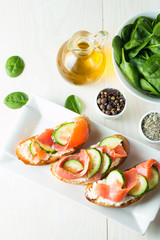 Salmon, cucumber and cream cheese bruschetta. Italian tapas, antipasti with vegetables, herbs and oil on grilled ciabatta and baguette bread. Sandwich.