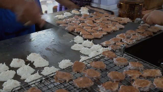Vendors cooking authentic Thai dessert called Kanom Babin on a hot griddle. Traditional sweet coconut pancake frying for sale in a local market in Bang Kachao, street food in Thailand.vegan,halal food